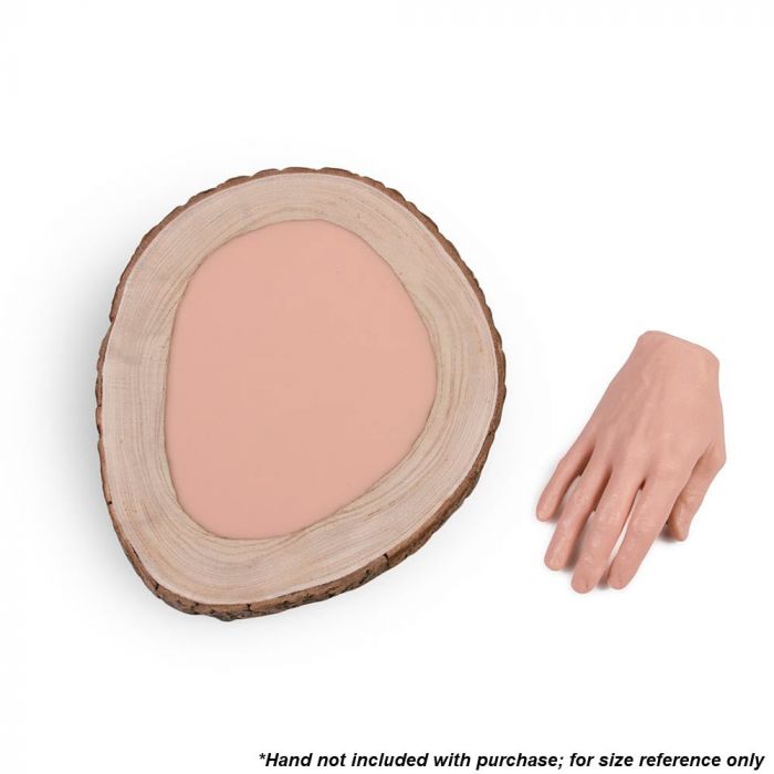 Tattooable flesh imbedded in a frame that looks like a wooden slab from the branch of a tree. This product is posed in front of a white background next to a tattooable hand.